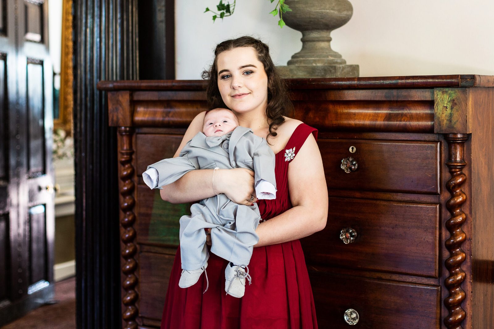 A bridesmaid in red holds a sleeping baby