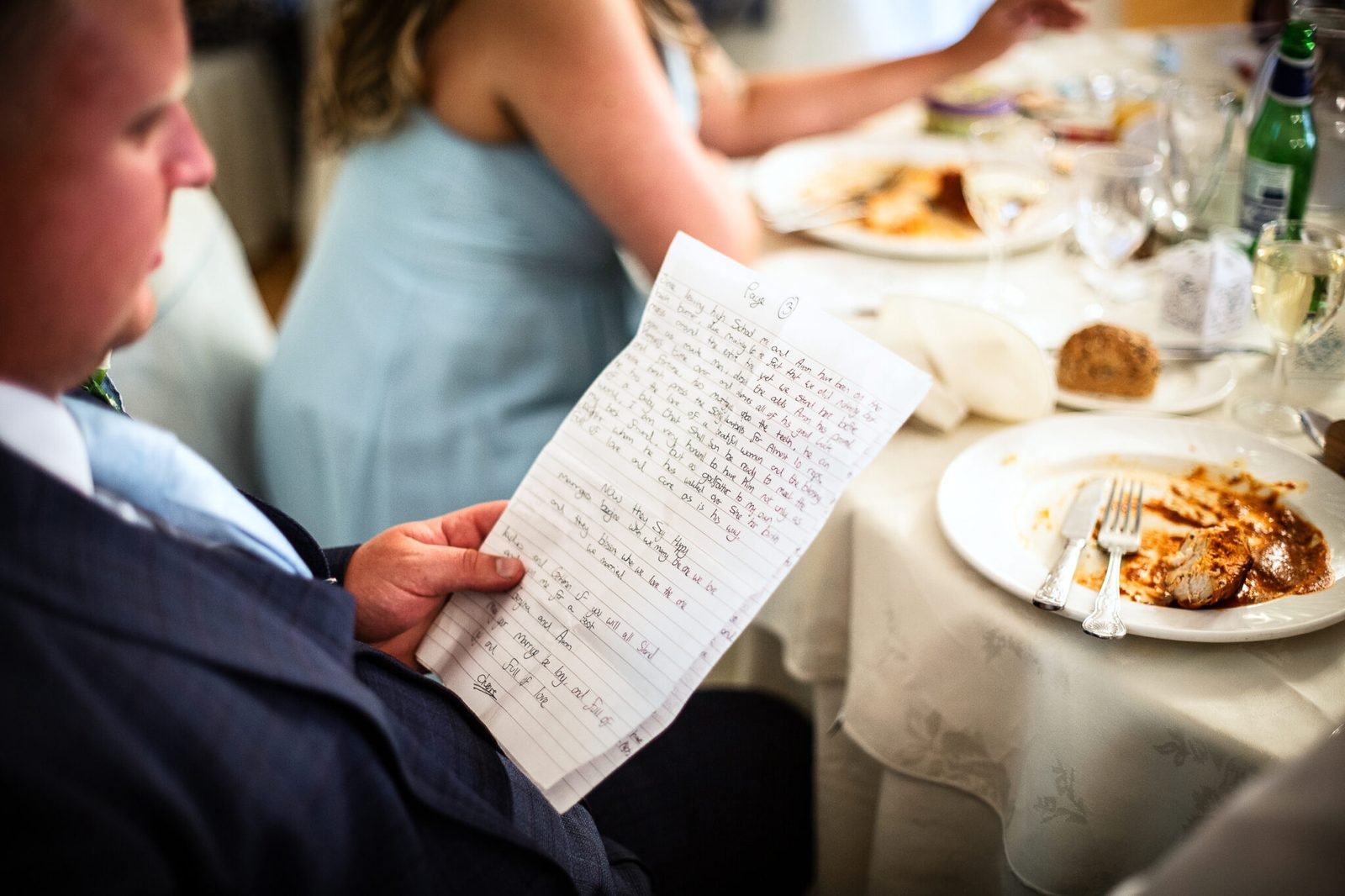 A guest holds handwritten speech notes above the dinner table