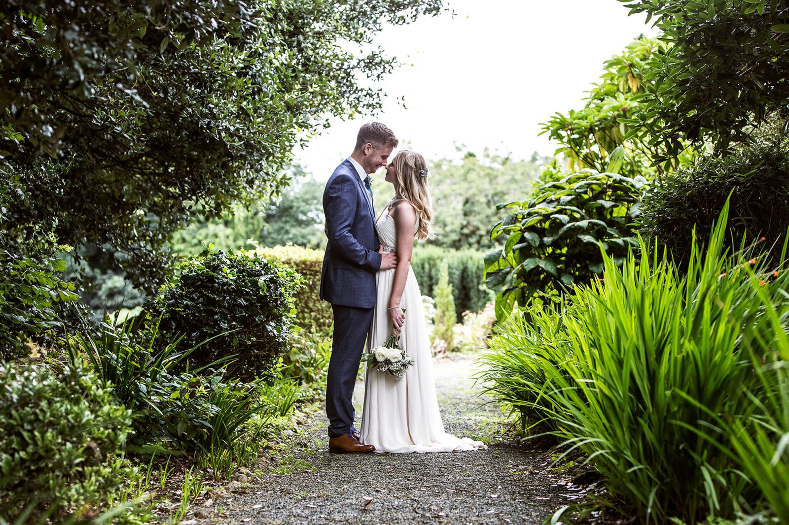 A couple share a kiss among green garden planting