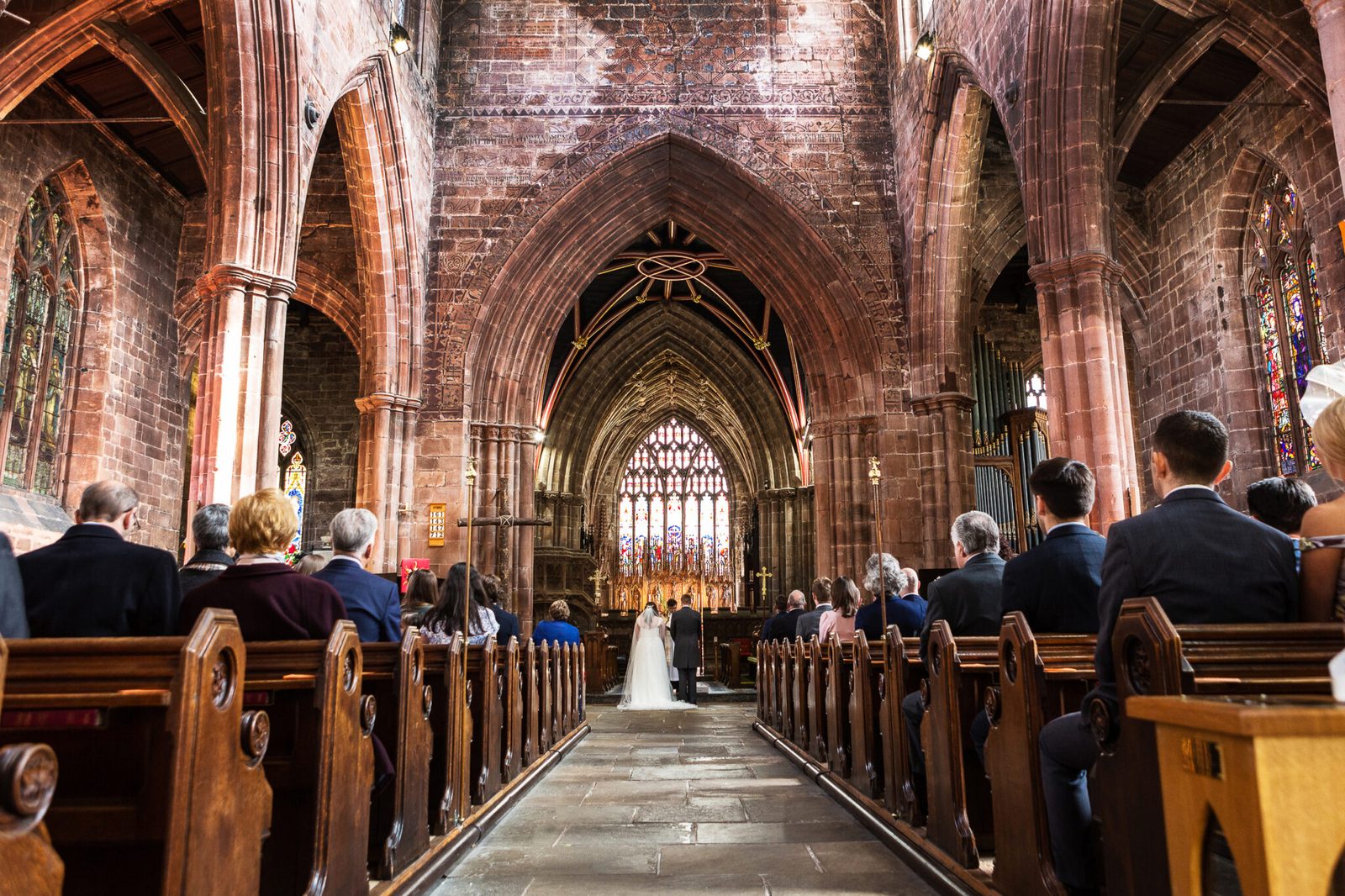 A red sandstone church nave with guests in the pews