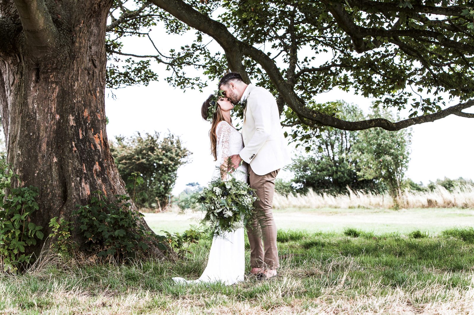 A couple kiss beneath the spreading branches of an old tree