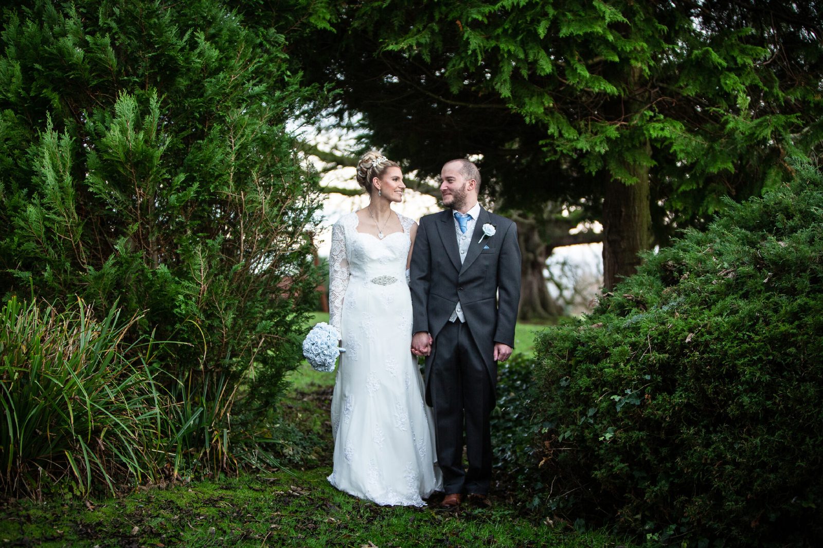 A bride and groom walk together through a garden