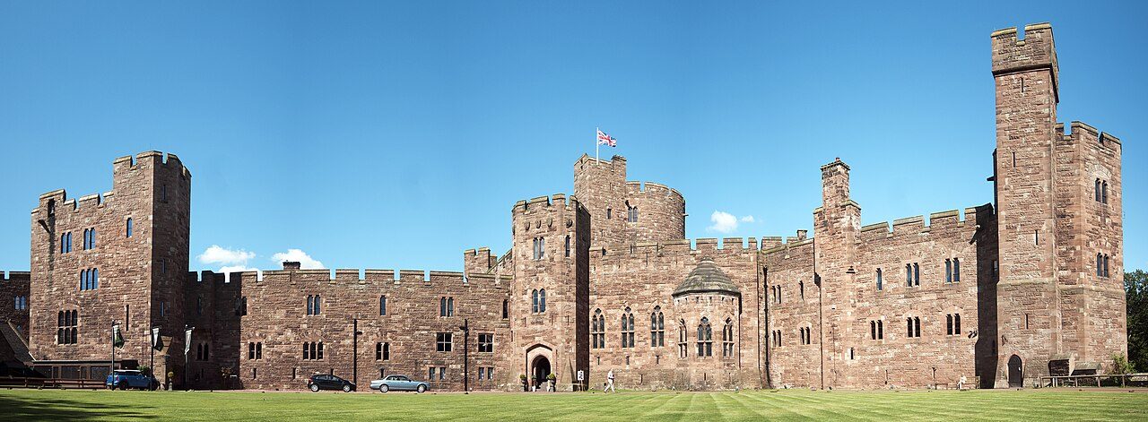 Peckforton Castle's sandstone towers and curtain wall under a blue sky