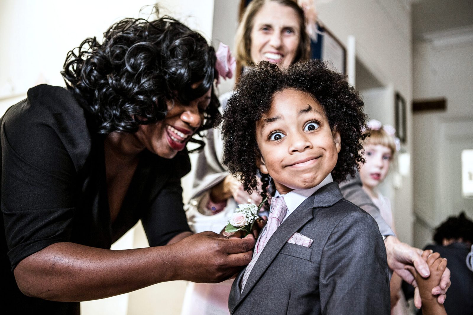 A young boy pulls a funny face as his buttonhole is pinned