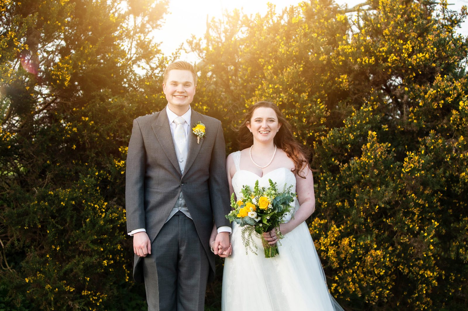 A couple smile in front of flowering gorse