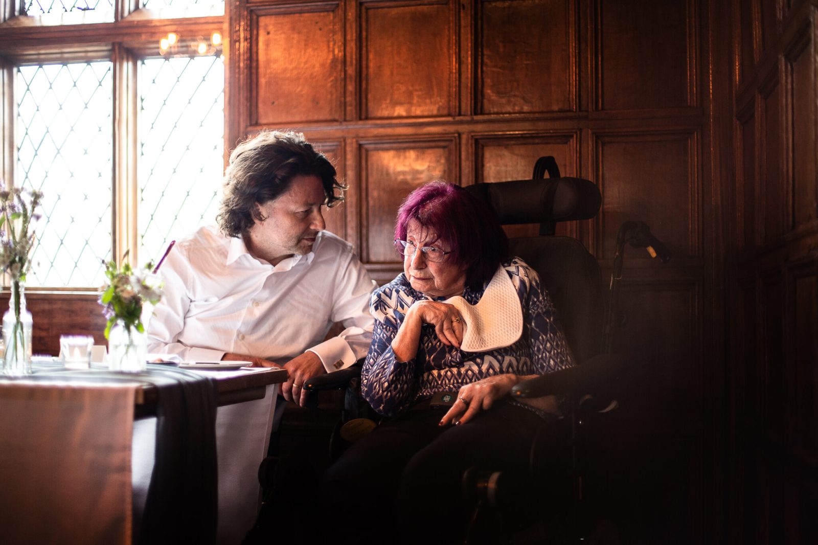 Guests talk quietly at a table in a wood-panelled room
