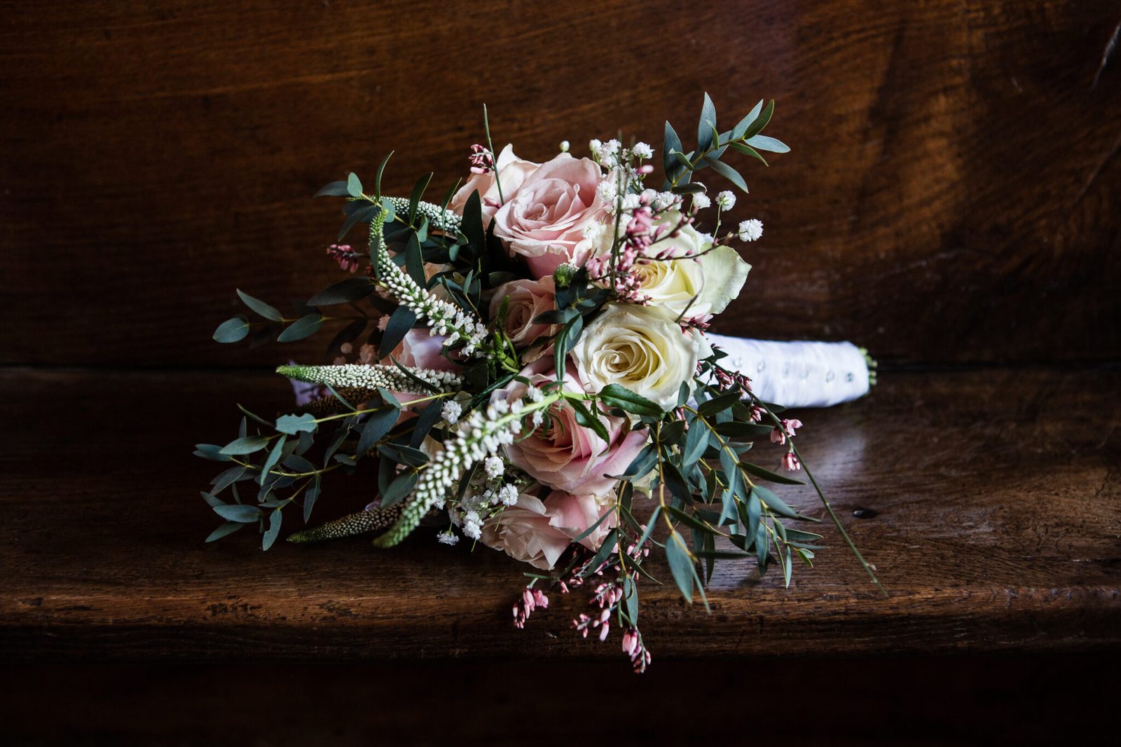A bouquet of pale roses resting on dark wood