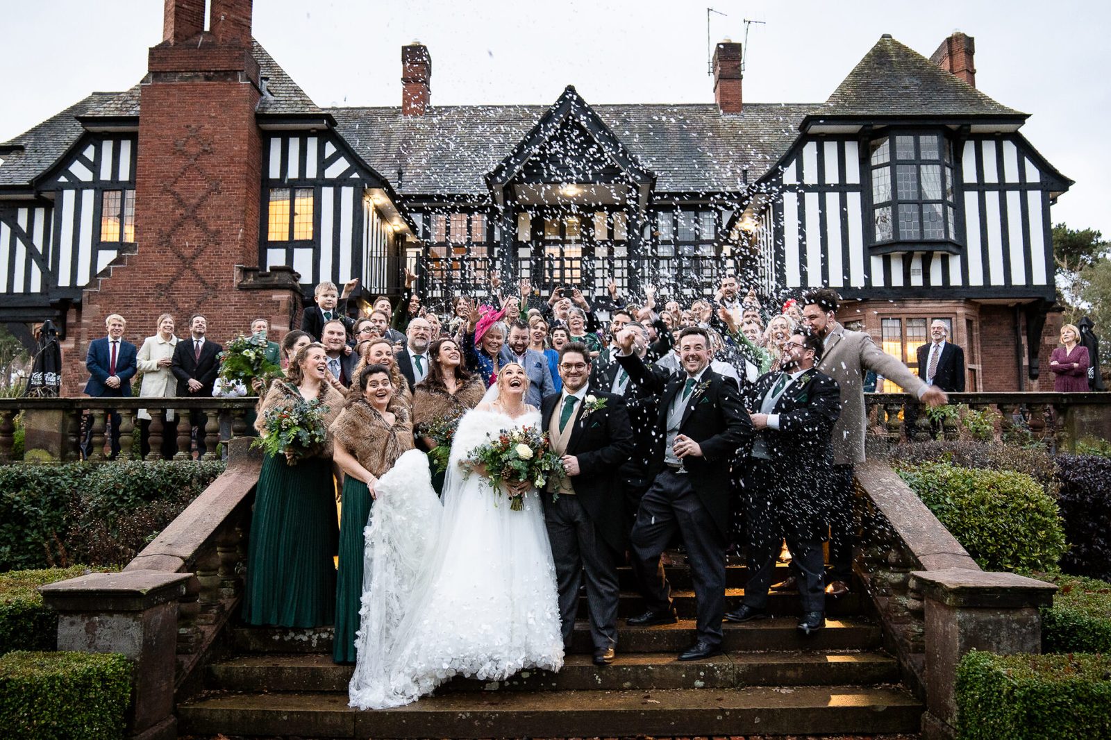 A large group of guests in front of a timber-framed hall