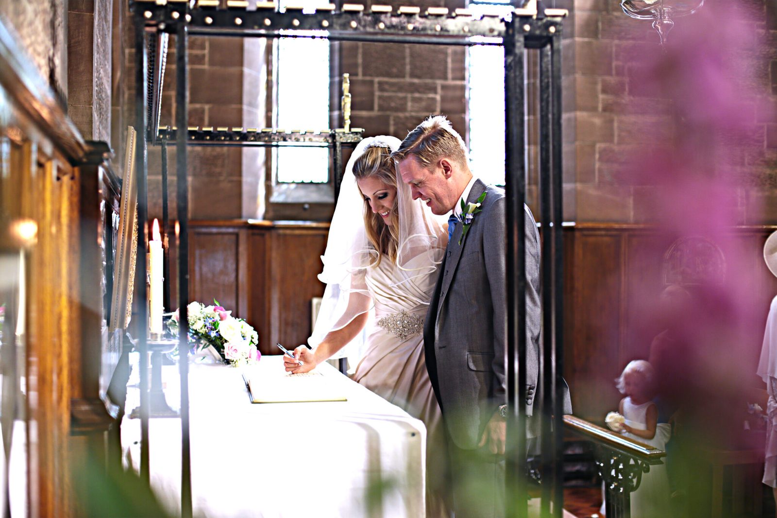 A couple sign the register, framed by flowers in the foreground