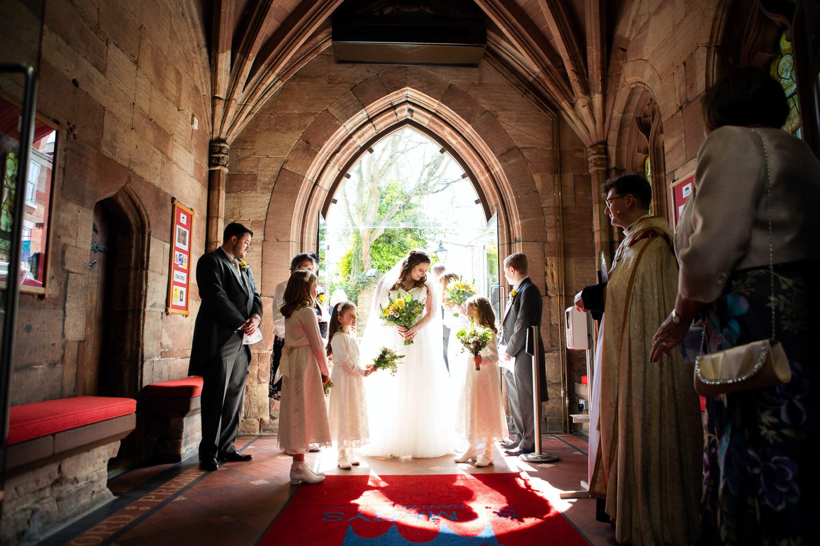A bride enters a church through a bright arched doorway