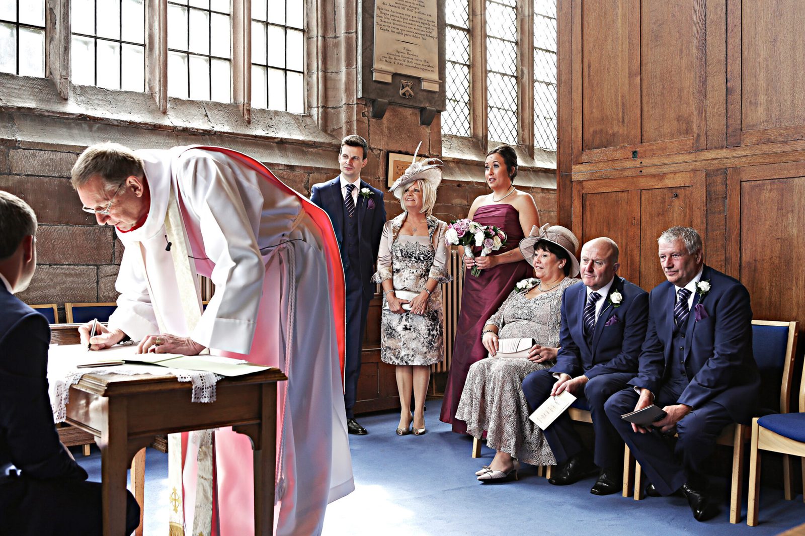 The minister signs the register while family watch from the front pews