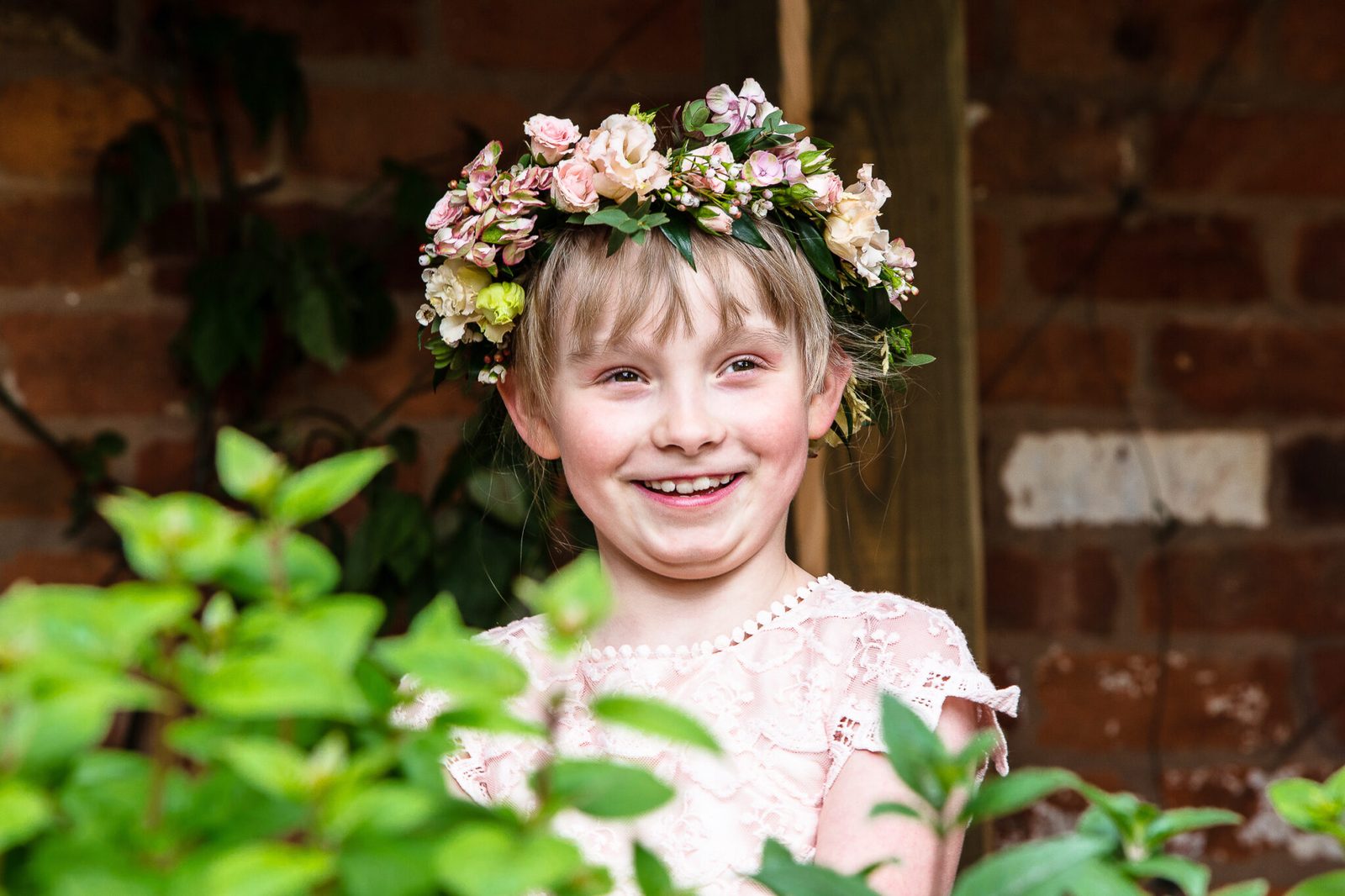 A girl in a flower crown smiles among leaves